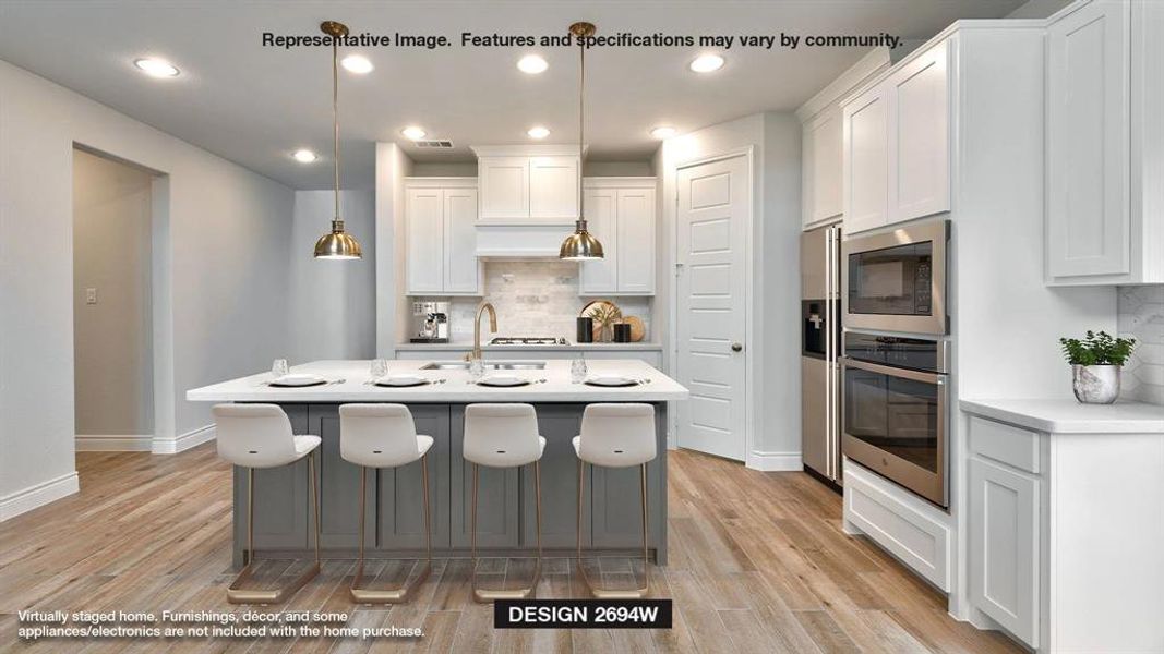 Kitchen featuring backsplash, appliances with stainless steel finishes, white cabinetry, pendant lighting, and light hardwood / wood-style floors