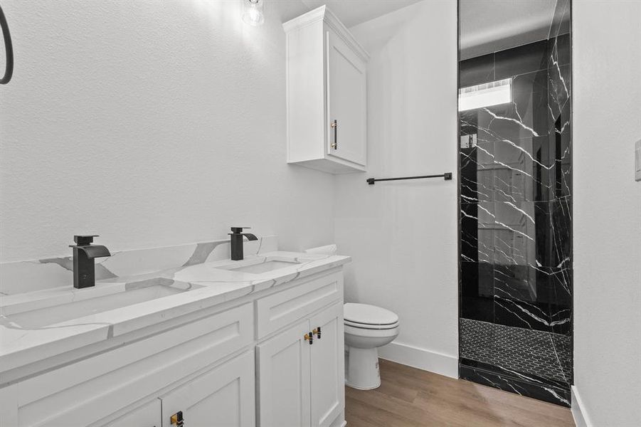 Bathroom featuring vanity, toilet, hardwood / wood-style floors, and tiled shower