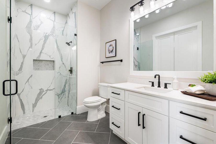 Bathroom with tile patterned flooring, toilet, a shower with door, and vanity