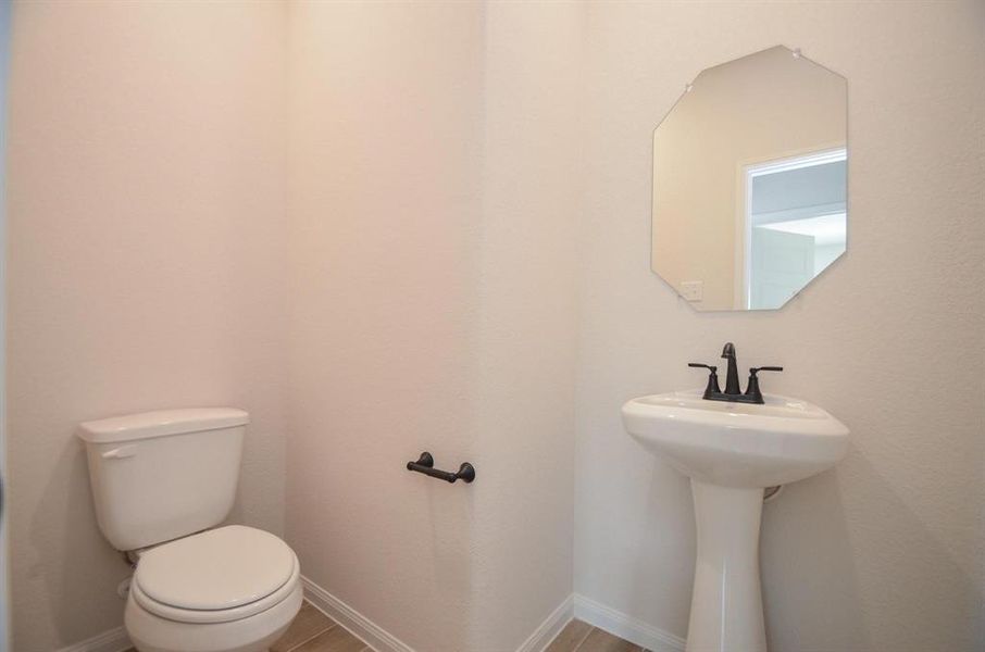 A sleek and modern powder room, featuring a pedestal sink and understated elegance. Perfectly situated for guests, this space blends convenience with minimalist style.