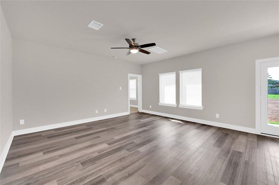 Your spacious new living area features tall ceilings, gorgeous luxury vinyl plank flooring, neutral paint, and gorgeous views of your large backyard through gleaming double pane windows. Enter your primary suite through the door straight ahead!