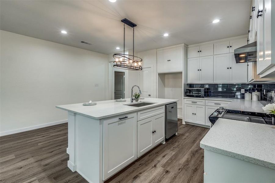 Kitchen with a center island with sink, decorative backsplash, dark wood-type flooring, and white cabinets