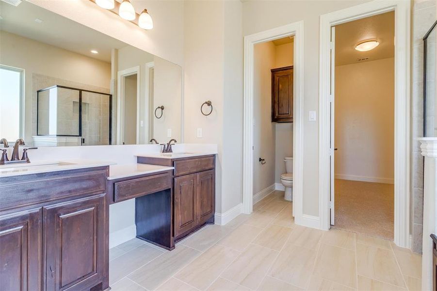 Bathroom featuring toilet, walk in shower, tile patterned floors, and vanity