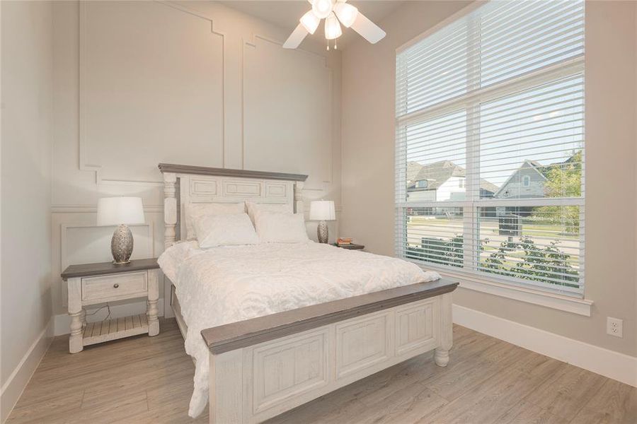 Secondary Bedroom with double windows, light tones, ceiling fan and paneled wall!