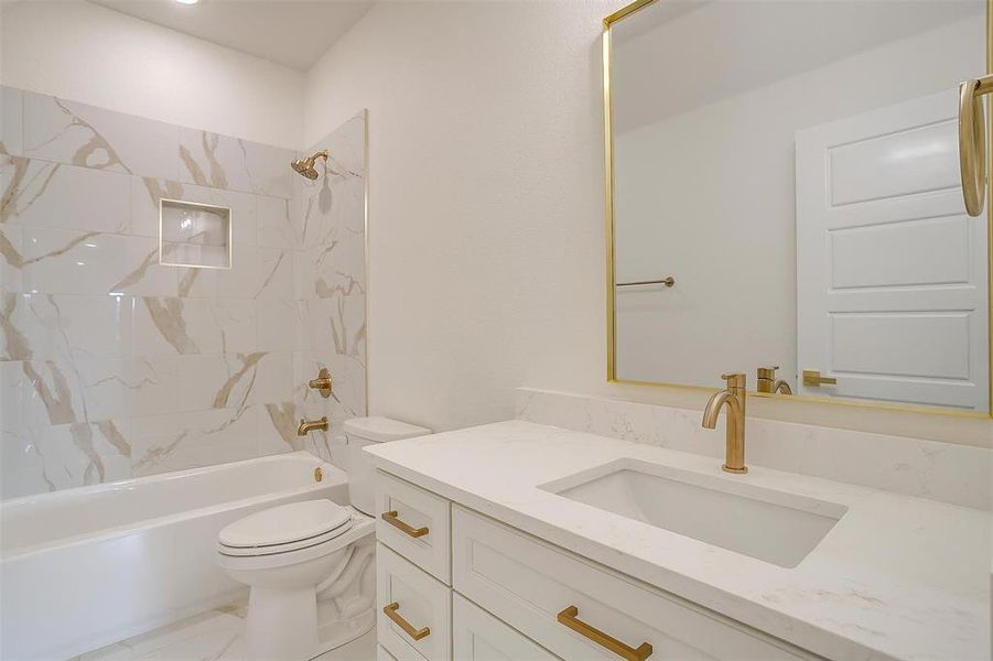 Full bathroom featuring vanity, tiled shower / bath combo, and toilet