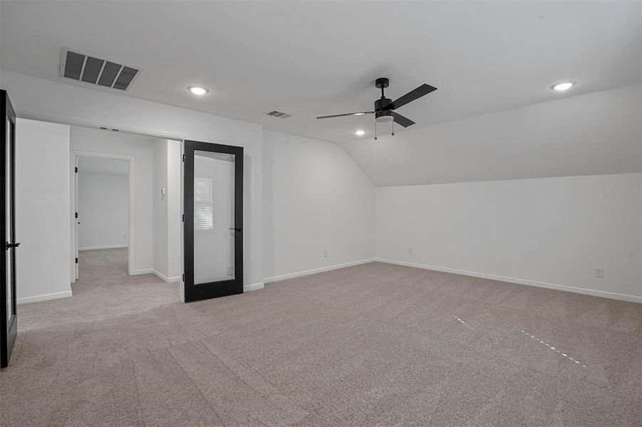 Additional living space featuring light carpet, vaulted ceiling, and ceiling fan