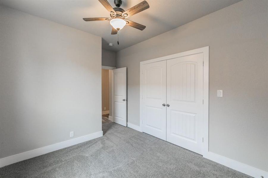 Unfurnished bedroom featuring carpet flooring, a closet, and ceiling fan