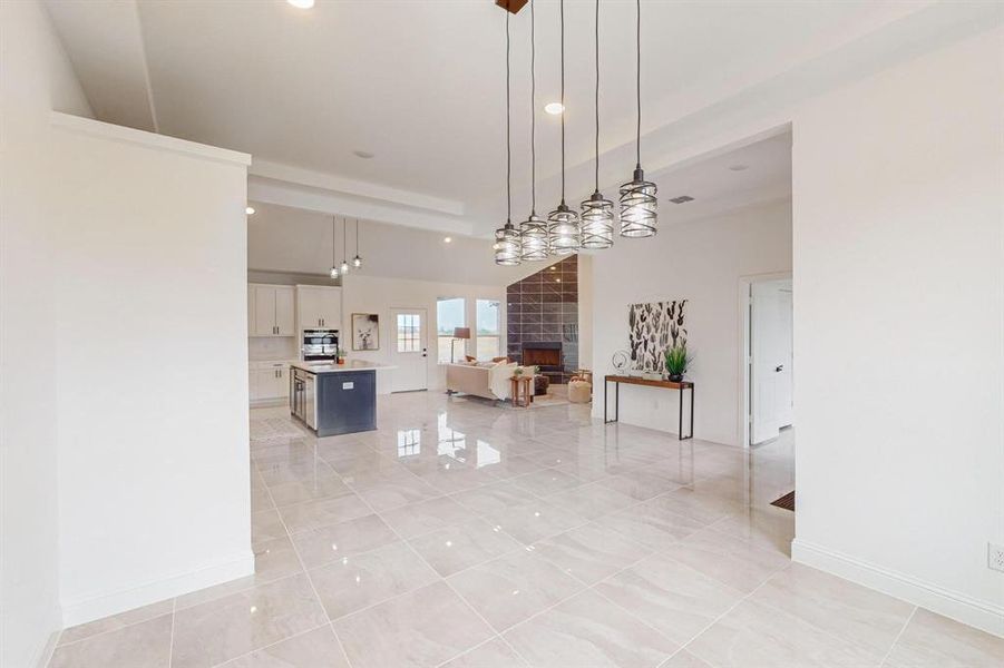 Kitchen with a fireplace, oven, a kitchen island, white cabinets, and pendant lighting