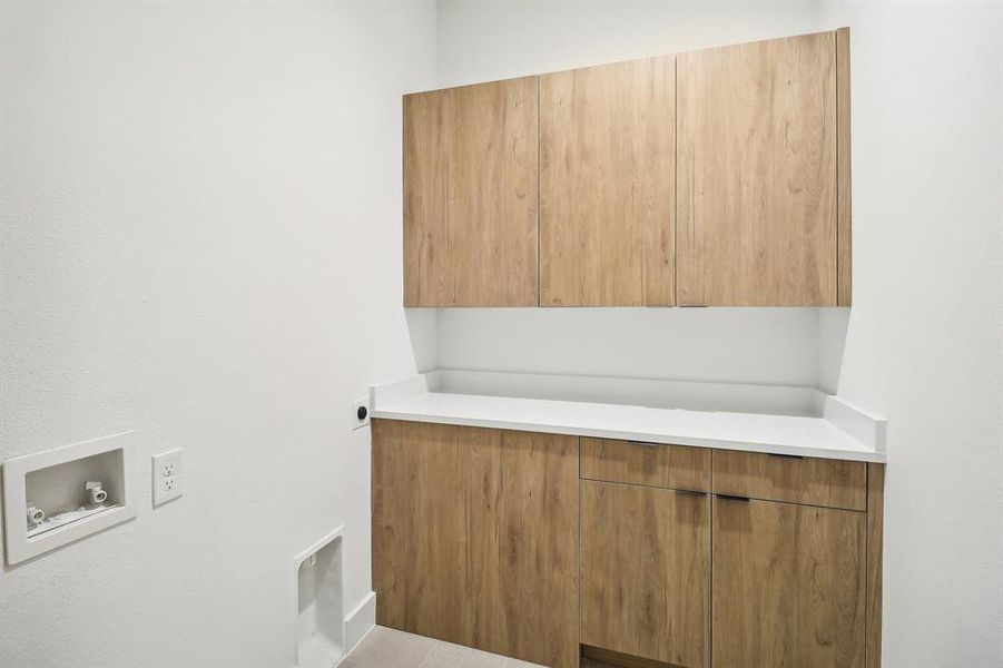 Laundry area with hookup for an electric dryer, light tile patterned flooring, washer hookup, and cabinets