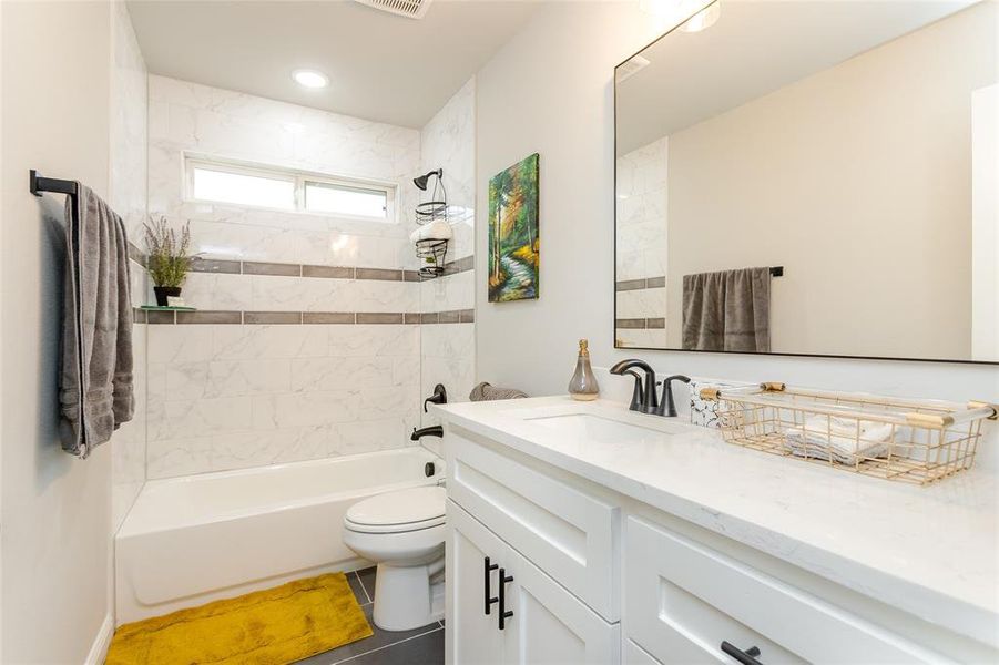 Full bathroom with vanity, toilet, tile patterned floors, and tiled shower / bath