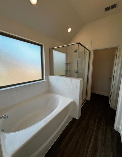 Bathroom with shower with separate bathtub, vaulted ceiling, and hardwood / wood-style floors