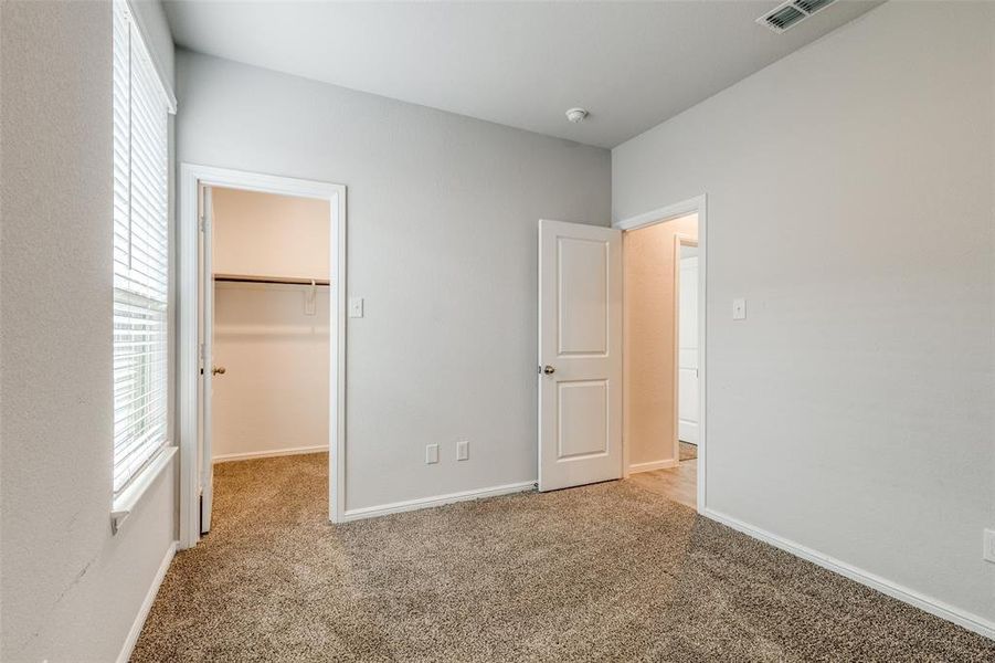 Unfurnished bedroom with a closet, carpet, and a walk in closet