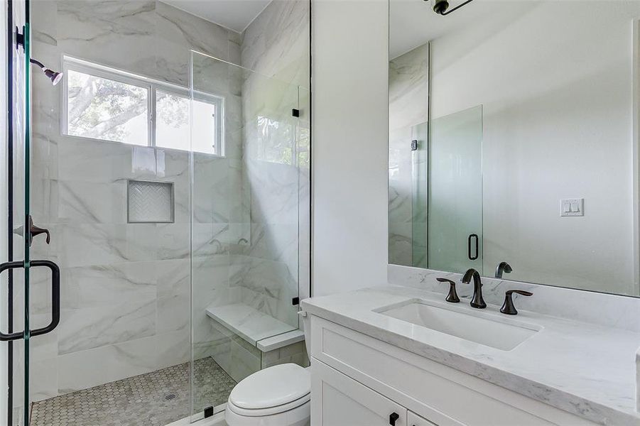 This secondary bathroom features a luxe walk-in shower with a privacy window that allows in natural light.