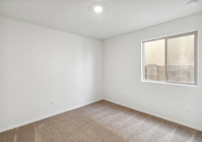 Guest bedroom with recessed lighting, tan carpet, and windows.