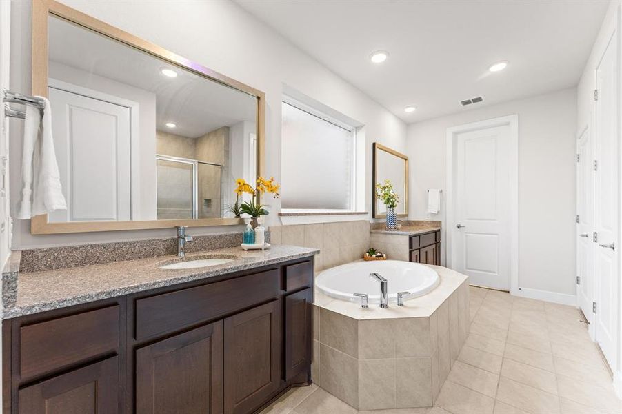 The spa-like en suite bathroom offers luxurious amenities, including separate double vanities for convenience and elegance. It features a soaking tub perfect for relaxation and a separate shower for added comfort and functionality, providing a serene retreat within the master suite....