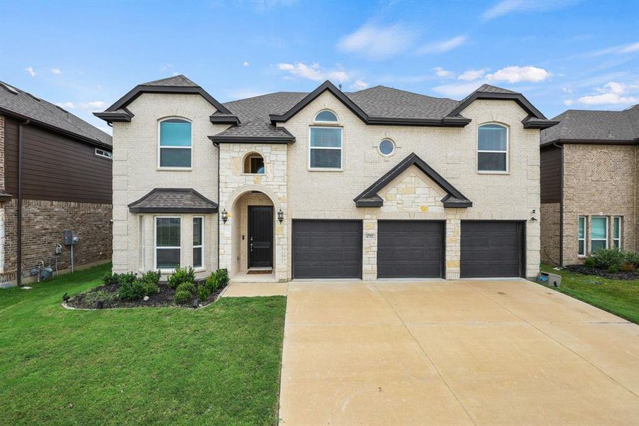 French country inspired facade featuring a front lawn and a garage