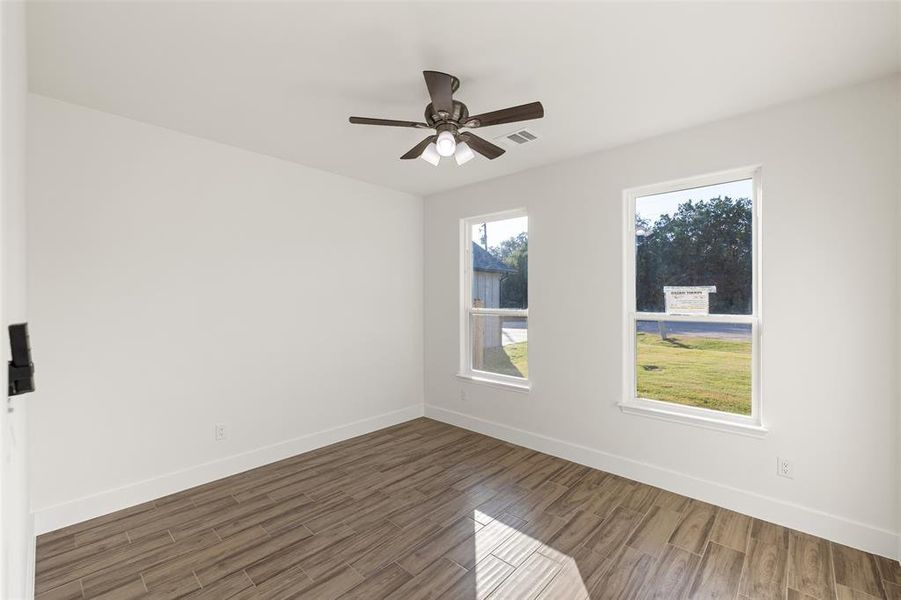 Empty room with ceiling fan and dark hardwood / wood-style floors