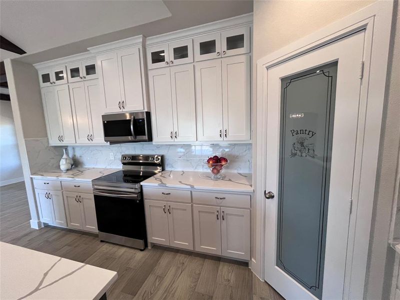 Kitchen featuring appliances with stainless steel finishes, backsplash, and white cabinetry