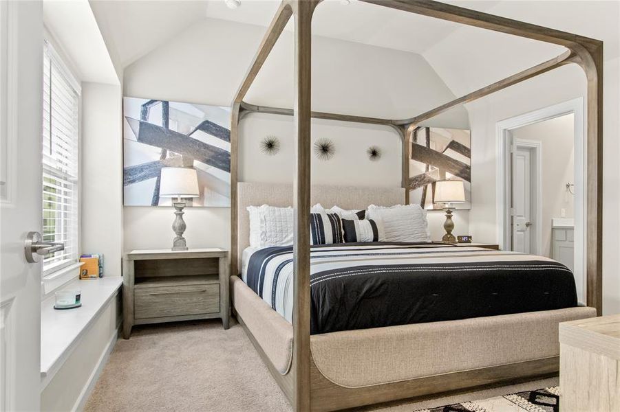 Bedroom featuring light colored carpet, vaulted ceiling, and connected bathroom