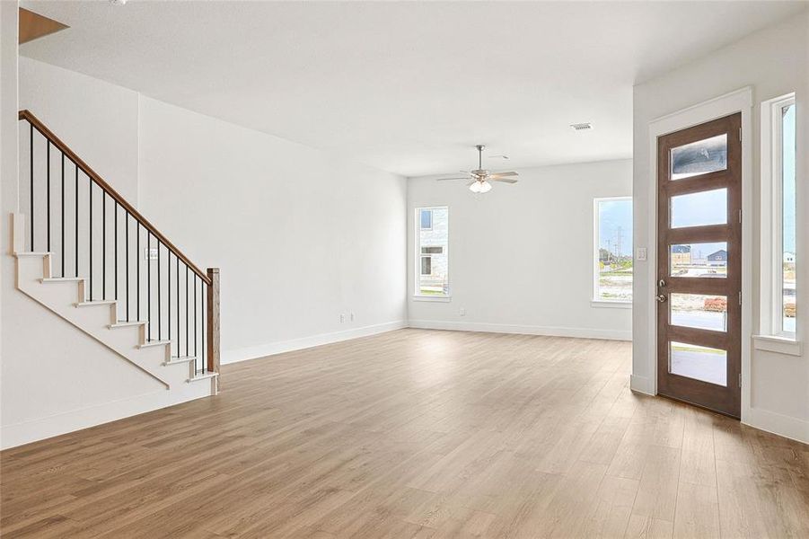 Unfurnished living room with light wood-type flooring, ceiling fan, and a healthy amount of sunlight