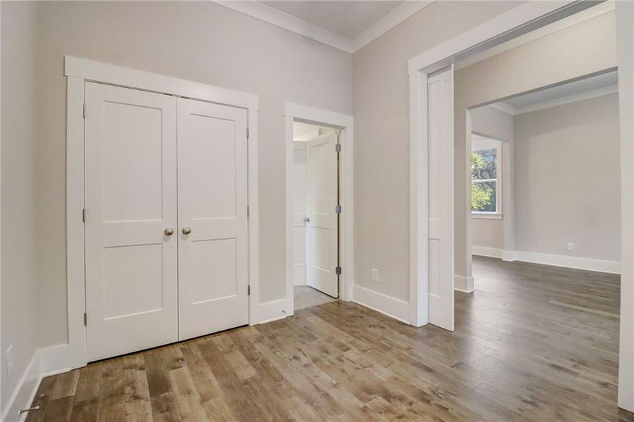 Unfurnished bedroom with crown molding, a closet, and light hardwood / wood-style floors