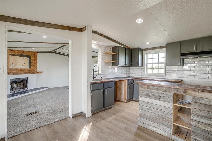 Kitchen with lofted ceiling with beams, tasteful backsplash, sink, and light hardwood / wood-style floors