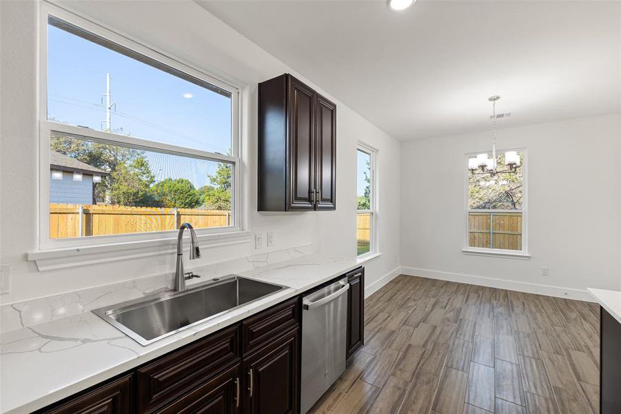 Kitchen with light hardwood / wood-style floors, pendant lighting, a notable chandelier, sink, and dishwasher