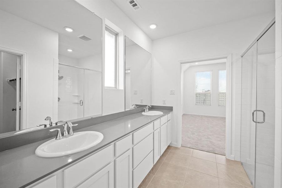 This is a bright, Spacious Primary bathroom with a Quartz countertops dual-sink vanity, large mirror, glass-enclosed oversize shower, and a separate toilet area visible through an archway. It features natural light Large Walk-in closet with wood shelving for organizing your closet.