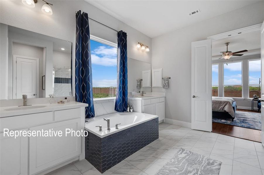 Bathroom featuring a healthy amount of sunlight, a relaxing tiled bath, large vanity, and tile floors