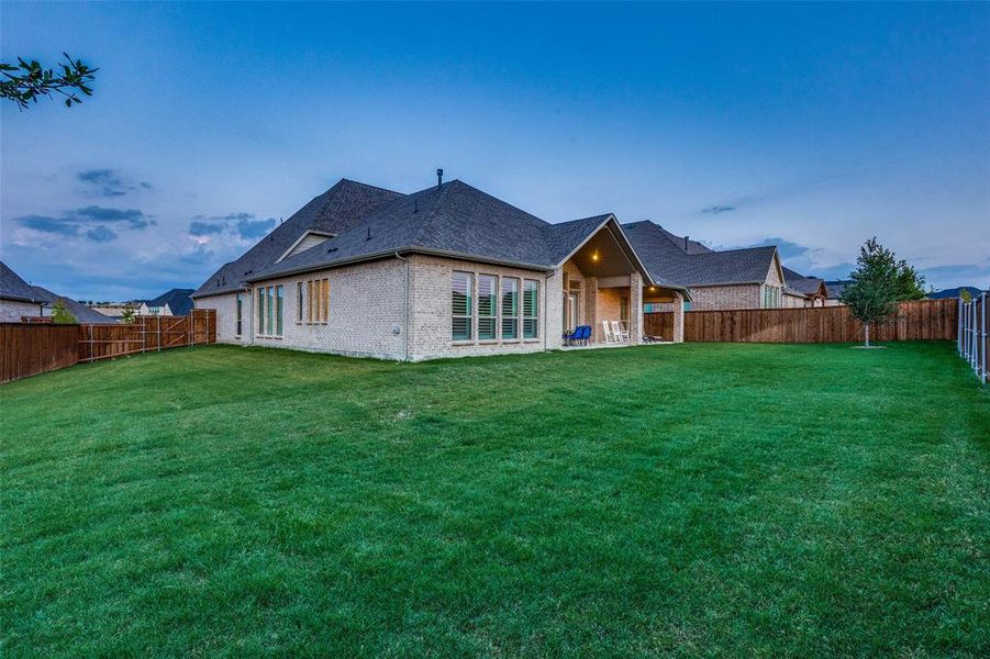 Back house at dusk featuring a lawn