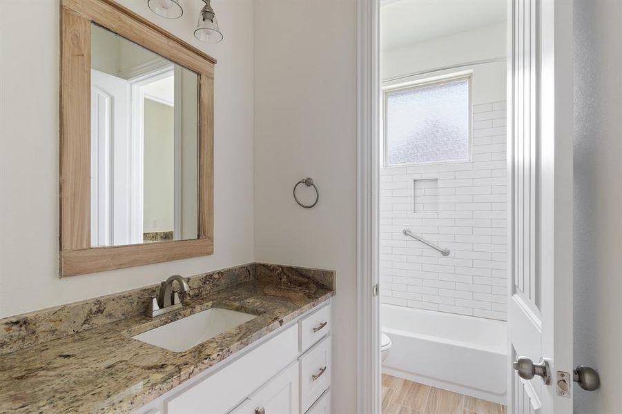 Full bathroom featuring tiled shower / bath combo, toilet, and vanity