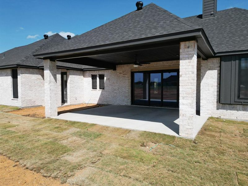 Rear view of property with a patio, ceiling fan, and a lawn