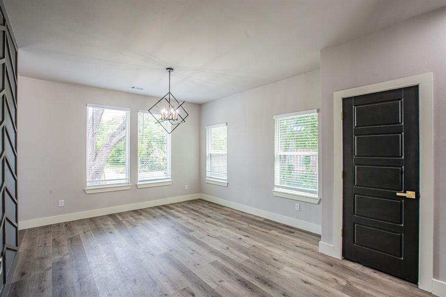 Spare room featuring an inviting chandelier and light hardwood / wood-style flooring