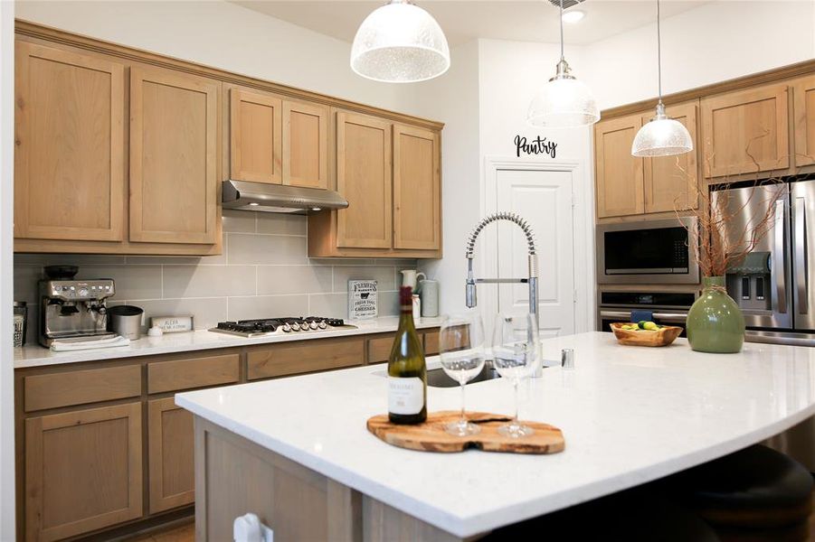 Kitchen with a kitchen island, appliances with stainless steel finishes, pendant lighting, and backsplash