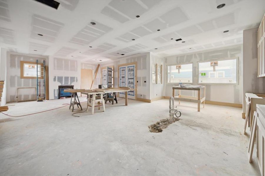 Another breathtaking view of the kitchen reveals its seamless flow into the bright and airy breakfast area, where two grand windows invite a flood of natural light. Elegant French doors open gracefully to the backyard, extending the living space outdoors for effortless entertaining. This thoughtfully designed open-concept floor plan beautifully combines the living room and kitchen, anchored by a sophisticated fireplace and the promise of custom built-ins, creating a space that’s both luxurious & welcoming.