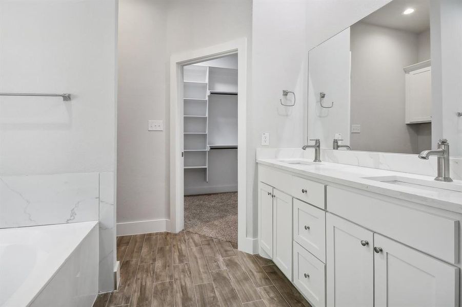 Bathroom with vanity, hardwood / wood-style flooring, and a tub