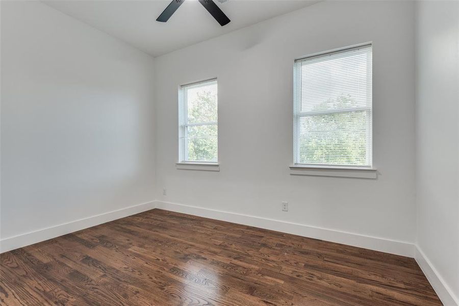 Secondary bedroom with ceiling fan and hardwood floors.