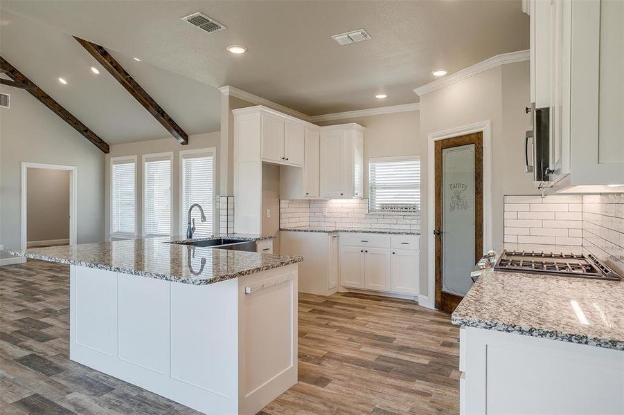 Kitchen featuring white cabinetry, light granite countertops, farm sink, and a wealth of natural light