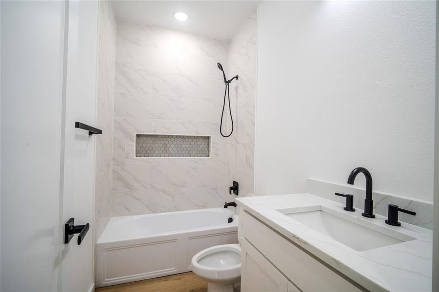 Full bathroom with tiled shower / bath, vanity, toilet, and hardwood / wood-style flooring