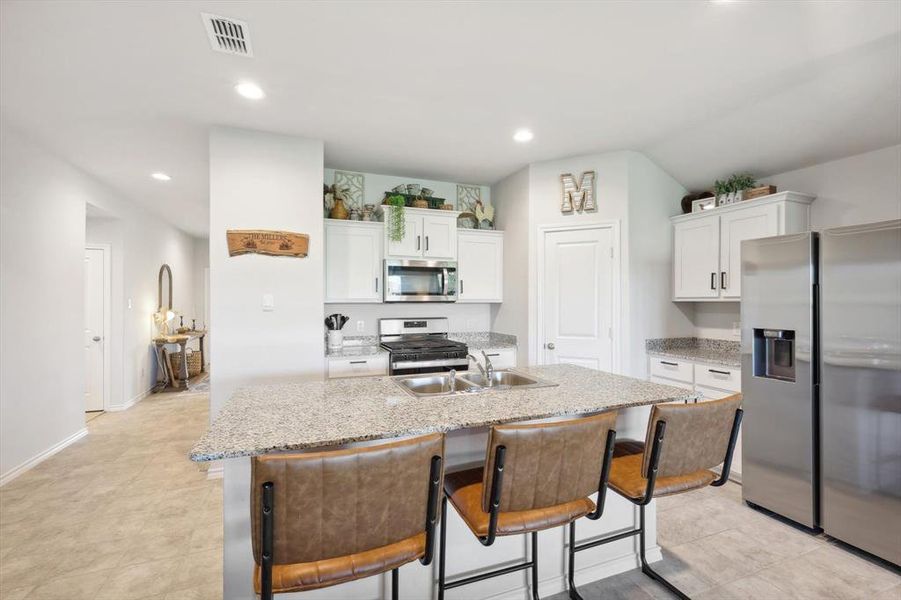 Kitchen featuring appliances with stainless steel finishes, a center island with sink, white cabinetry, and sink