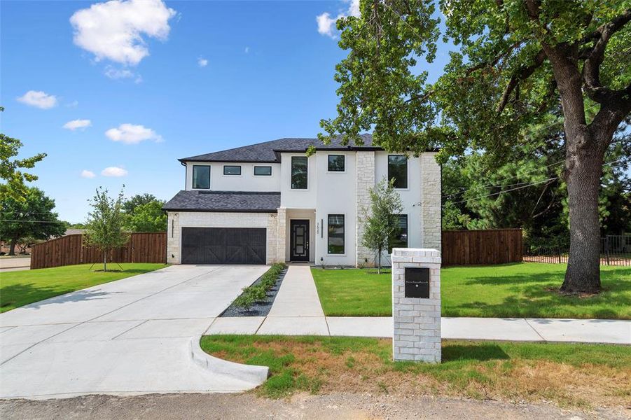 View of front of property featuring a front lawn and a garage