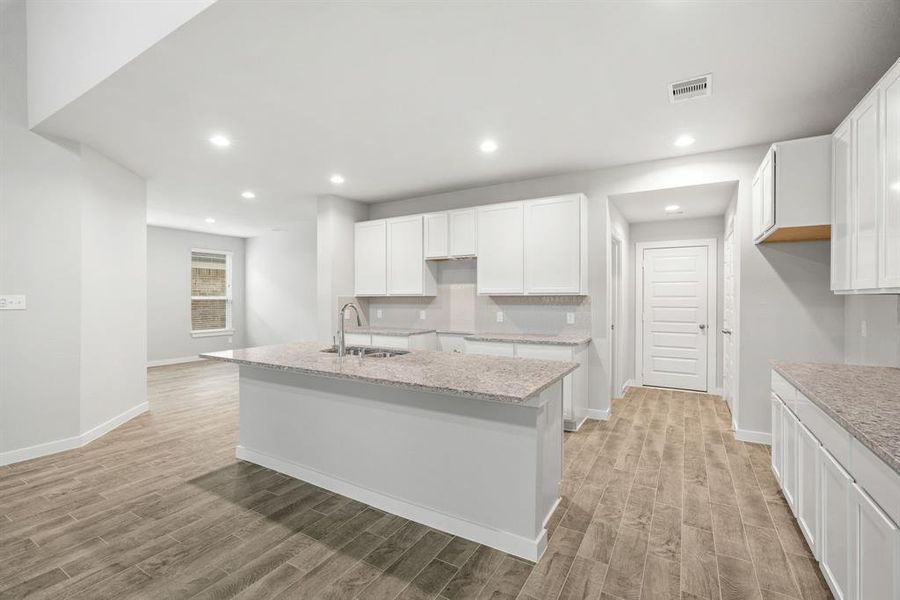 Discover another perspective of this stunning kitchen, generously appointed with an abundance of counter space. Sample photo of completed home with similar floor plan. As-built interior colors and selections may vary.