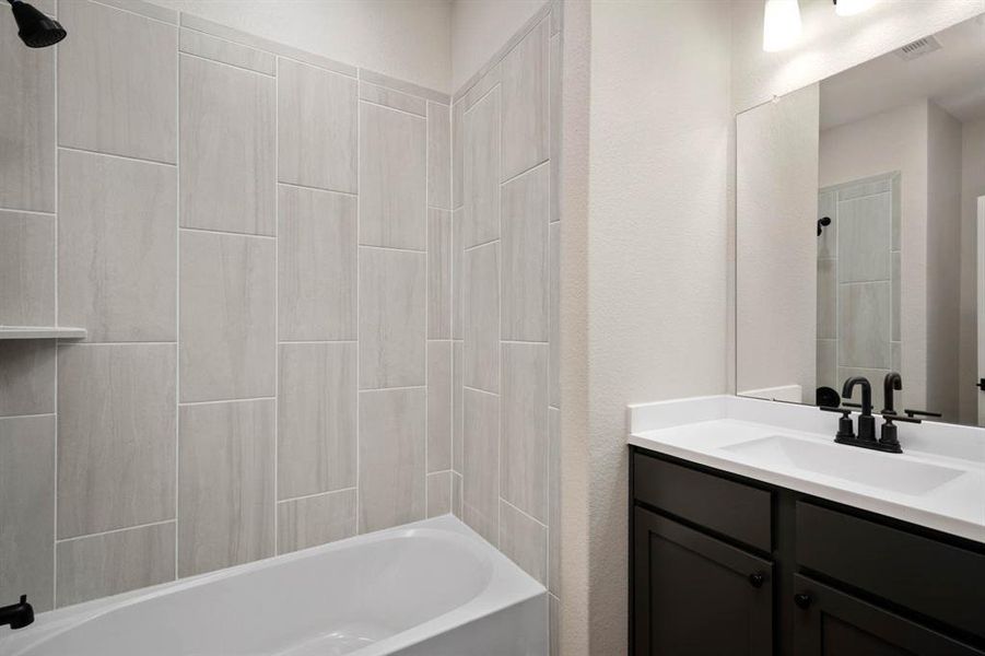 The spare bathroom has beautiful, upgraded tile and cabinetry for storage.