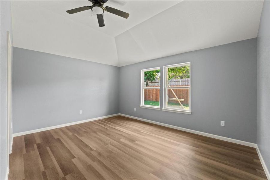 Empty room featuring hardwood / wood-style flooring, lofted ceiling, and ceiling fan