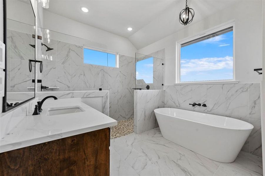 Bathroom with tile floors, tile walls, separate shower and tub, and vanity