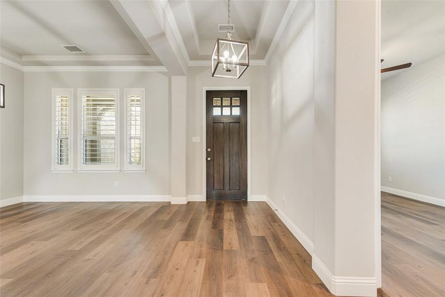 Entryway featuring an inviting chandelier, a wealth of natural light, hardwood / wood-style flooring, and ornamental molding