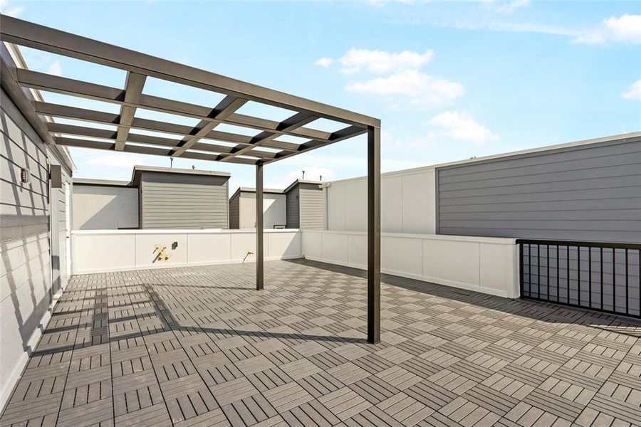 This is a spacious, modern rooftop terrace with a pergola, offering an open-air space suitable for entertainment or relaxation, with privacy fencing and a sleek, contemporary design.