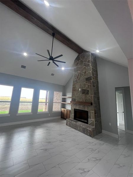 Unfurnished living room featuring beam ceiling, a fireplace, high vaulted ceiling, and ceiling fan