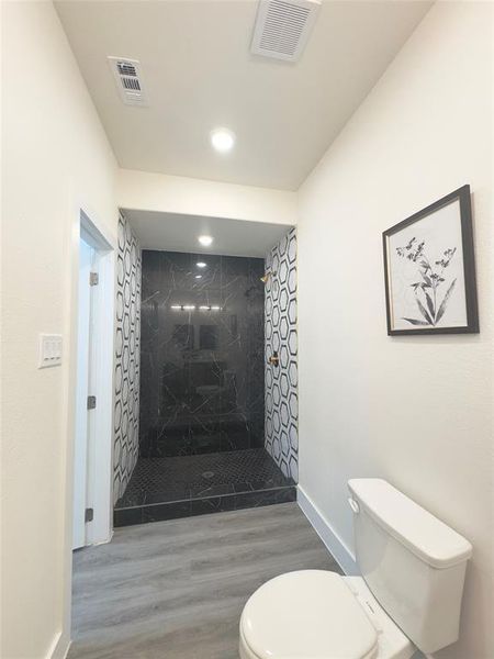 Bathroom featuring toilet, a tile shower, and hardwood / wood-style floors