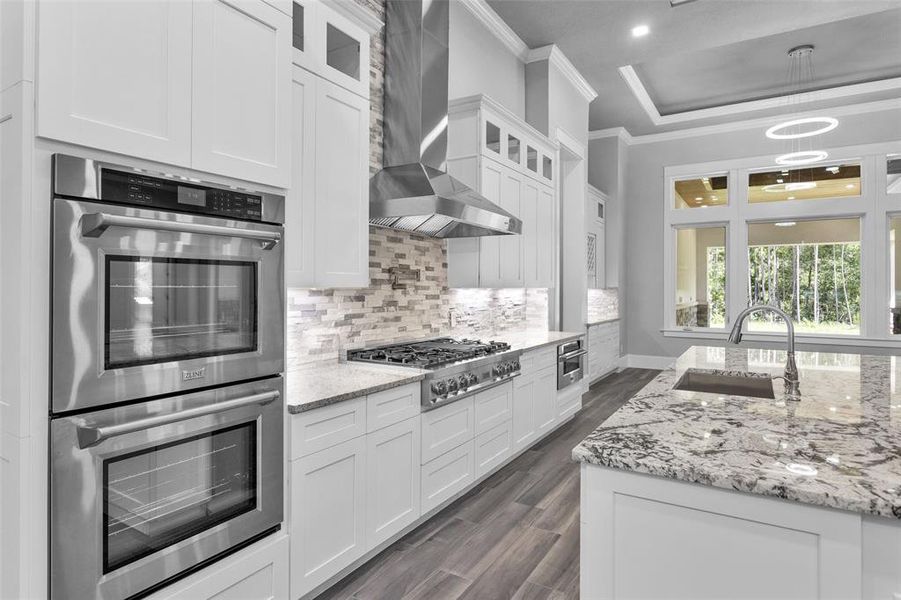 The Kitchen is finished with crisp, clean white cabinetry featuring glass doors at the top, along with beautiful rich "White Delicates" granite on the island and crisp clean white cabinetry and has tranquil views of the outdoor space and trees.